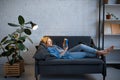 Young woman lying on cozy couch and reading a book Royalty Free Stock Photo