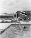 Young woman lying on a diving board with a young man hanging from it Royalty Free Stock Photo