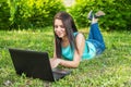 Young woman lying on the grass, using laptop and typing Royalty Free Stock Photo