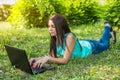 Young woman lying on the grass, using laptop and typing Royalty Free Stock Photo