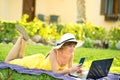 Young woman lying on green grass lawn working on computer laptop connected to wireless internet having conversation on mobile cell Royalty Free Stock Photo