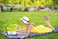 Young woman lying on green grass lawn working on computer laptop connected to wireless internet having conversation on mobile cell Royalty Free Stock Photo