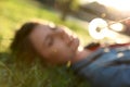 Young woman lying on green grass in park, focus on dandelion. Allergy free