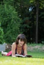 Young woman lying in green grass reading a book Royalty Free Stock Photo