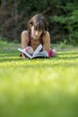 Young woman lying in green grass reading a book Royalty Free Stock Photo