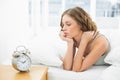 Young woman lying in her bed looking at the alarm clock Royalty Free Stock Photo