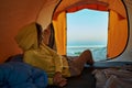 Young woman lying in her camping tent, overlooking the tranquil morning beach Royalty Free Stock Photo