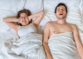 Young woman is lying with her husband in bed. Man is snoring too loud. Woman is covering her ears