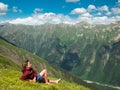 Young woman lying in a meadow with flowers in front of the North Caucasus mountain range Royalty Free Stock Photo