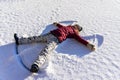 Young woman lying in the snow and making a snow angel. Winter walks and fun