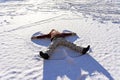 Young woman lying in the snow and making a snow angel. Winter walks and fun