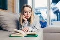 Young woman lying on sofa at home and reading a book. student girl studying lessons Royalty Free Stock Photo