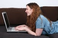 Young woman lying on sofa and using her laptop computer Royalty Free Stock Photo