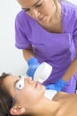 Young woman lying on a table with protect glasses on eyes getting a laser skin treatment