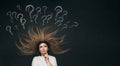 Young woman lying thinking with question mark written with chalk on school blackboard above head, brainstorming concept, girl