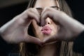 Young woman make heart symbol with fingers and send a kiss