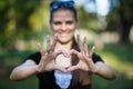Young woman makes hands in shape of love heart