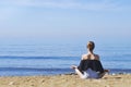Young woman makes meditation in lotus pose on sea / ocean beach, harmony and contemplation. Beautiful girl practicing yoga at sea Royalty Free Stock Photo