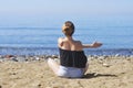 Young woman makes meditation in lotus pose on sea / ocean beach, harmony and contemplation. Beautiful girl practicing yoga at sea Royalty Free Stock Photo