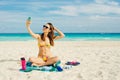 Young woman in a swimsuit in the sand makes selfie on the beach on her smartphone Royalty Free Stock Photo