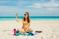 Young woman in a swimsuit in the sand makes selfie on the beach on her smartphone Royalty Free Stock Photo