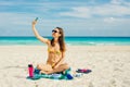 Young woman in a swimsuit in the sand makes selfie on the beach on her smartphone Royalty Free Stock Photo