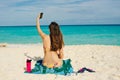 Young woman in a swimsuit in the sand makes selfie on the beach on her smartphone Royalty Free Stock Photo