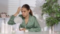 A young woman without makeup applying white cream on problem skin areas of the face. A woman in green silk pajamas Royalty Free Stock Photo