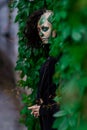 Young woman with Makeup of green skull for halloween surrounded by green leafs Royalty Free Stock Photo