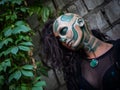Young woman with Makeup of green skull for halloween surrounded by green leafs Royalty Free Stock Photo