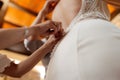 Young woman making adjustments to the back of a white wedding dress