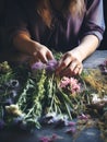 Young woman making a bouquet of summer wildflowers and herbs on a wooden table. Floral boutique, craftsmanship. Generative AI Royalty Free Stock Photo