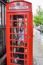 Young woman making a call in red telephone box, London, UK Royalty Free Stock Photo