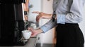 Young woman making coffee with coffee machine during office break time.