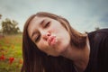 Young woman making duckface kiss while taking selfie picture with her smartphone or camera in field of red poppies Royalty Free Stock Photo