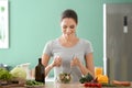 Young woman making fresh vegetable salad in kitchen Royalty Free Stock Photo