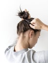 A young woman making hair bun isolated on white background