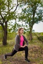 Young woman making lunge outdoors in summer. Physical exercises, wellbeing, fitness and healthy way of life concept. Royalty Free Stock Photo