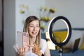 Young woman making photo or video content for social media with smartphone and light of ring lamp. Beauty blogger smiles Royalty Free Stock Photo