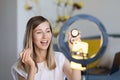 Young woman making photo or video content for social media with smartphone and light of ring lamp. Beauty blogger smiles Royalty Free Stock Photo