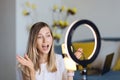 Young woman making photo or video content for social media with smartphone and light of ring lamp. Beauty blogger smiles Royalty Free Stock Photo