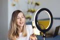 Young woman making photo or video content for social media with smartphone and light of ring lamp. Beauty blogger smiles Royalty Free Stock Photo