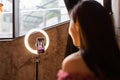 Young woman making photo or video content for social media with smartphone and light of ring lamp. Beauty blogger smiles Royalty Free Stock Photo