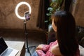 Young woman making photo or video content for social media with smartphone and light of ring lamp. Beauty blogger smiles Royalty Free Stock Photo