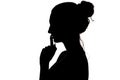 Young woman making a sign by finger near lips that means silence or secret, silhouette profile of unknown girl with a bun, privacy