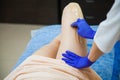 Young woman making sugaring hair removal procedure at beauty salon.