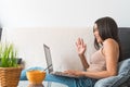 Young woman making video call sitting on sofa - Happy girl having fun doing video conference with family and friends Royalty Free Stock Photo