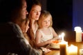 Young woman making a wish before blowing candles on her birthday cake. Family celebrating birhday