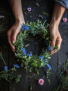 Young woman making a wreath of wildflowers on a wooden table. Florist creating midsummer decoration. midsummer