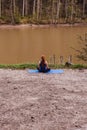 Young woman making yoga near river. Afar.